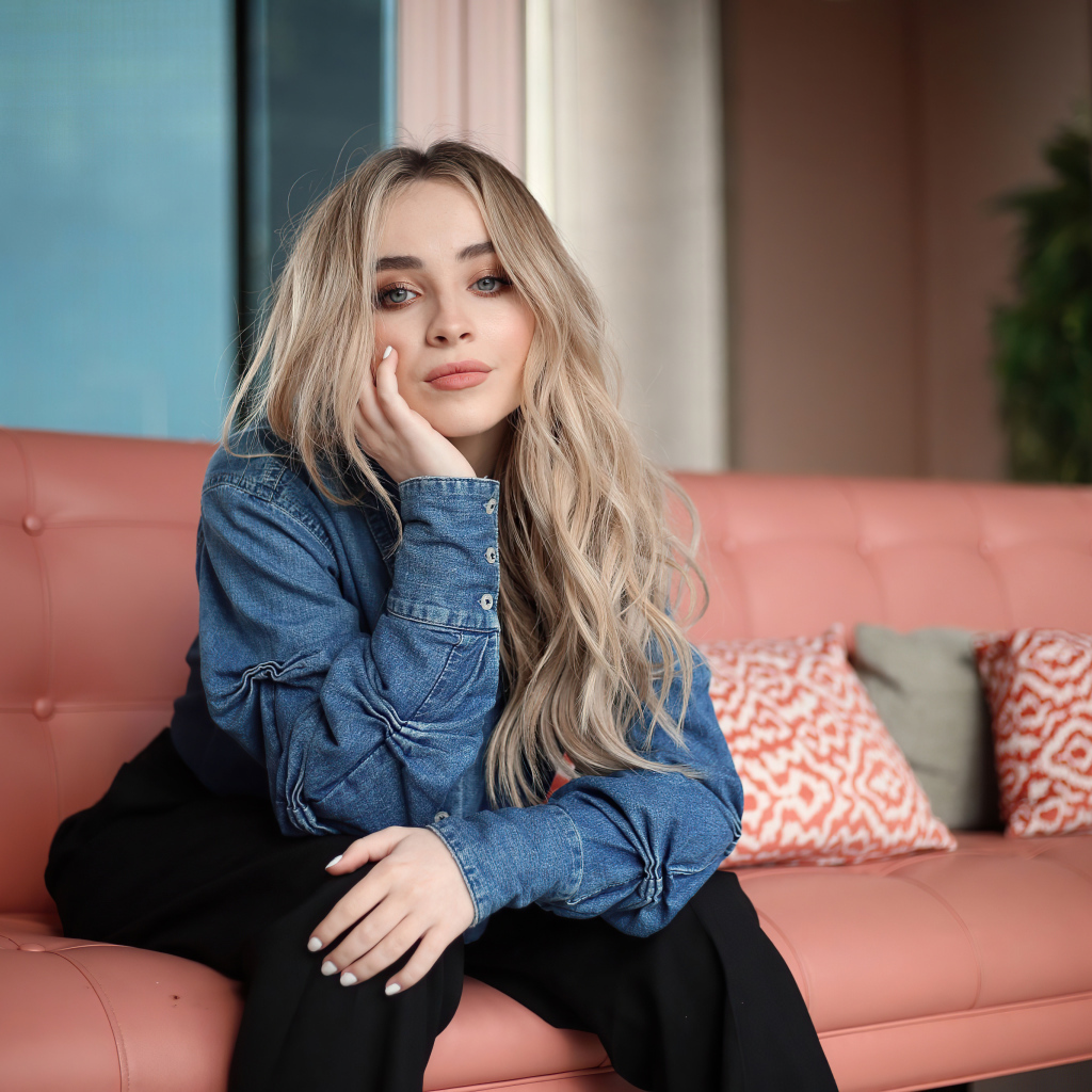 Актриса Сабрина Карпентер сидит на диване в комнате