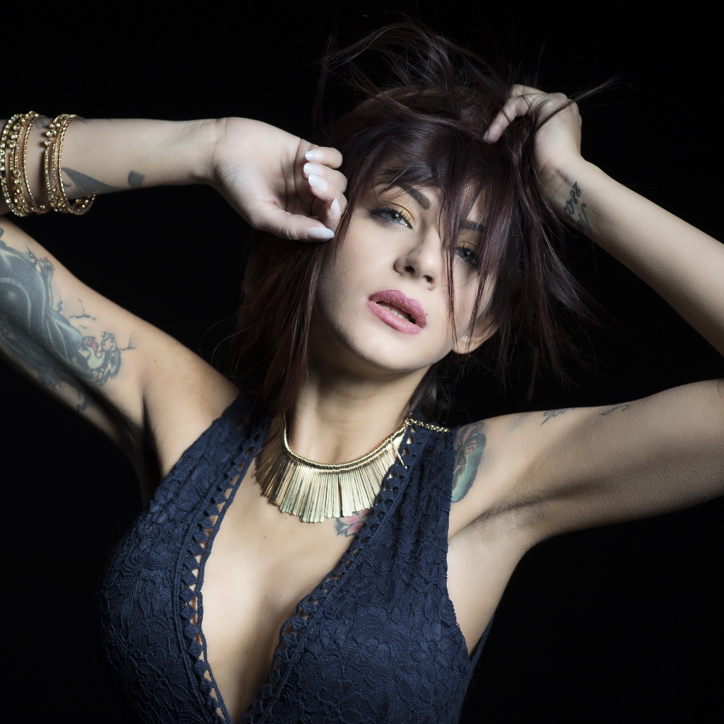 Красивая девушка в черном платье с татуировками на теле 