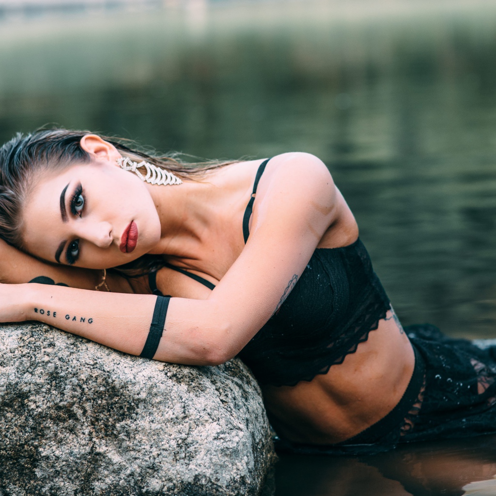 Красивая девушка в черном наряде с татуировками на руках 