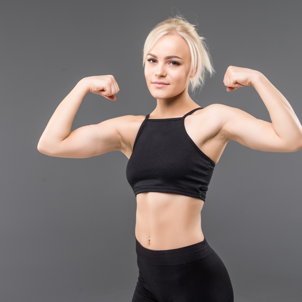 Красивая стройная спортивная девушка показывает мускулы