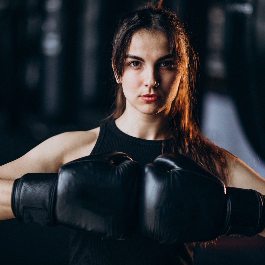 Девушка боксер с черными перчатками на руках 
