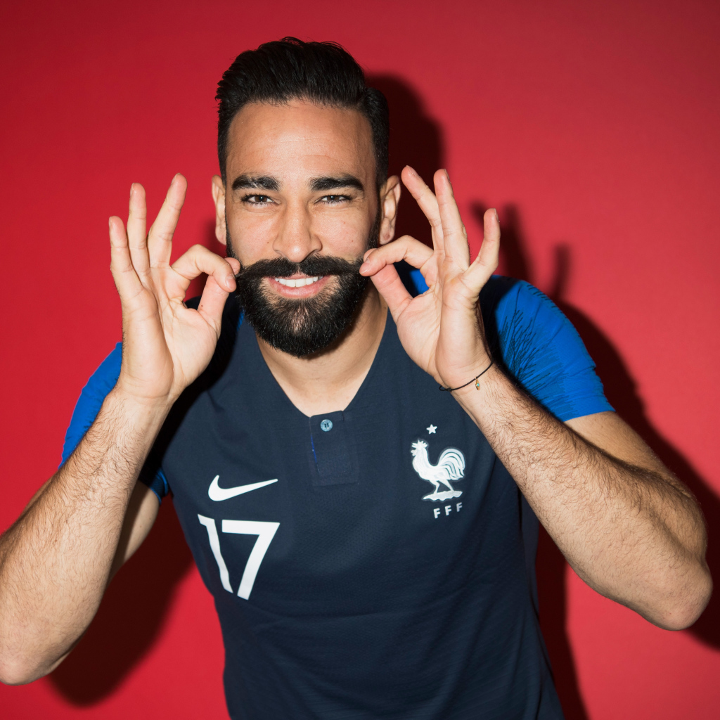 Французский футболист Адиль Рами на красном фоне