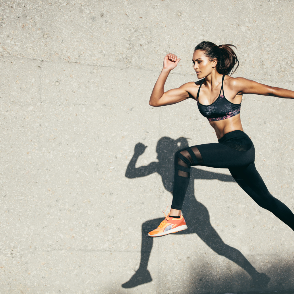 Девушка спортсменка бежит на стадионе 