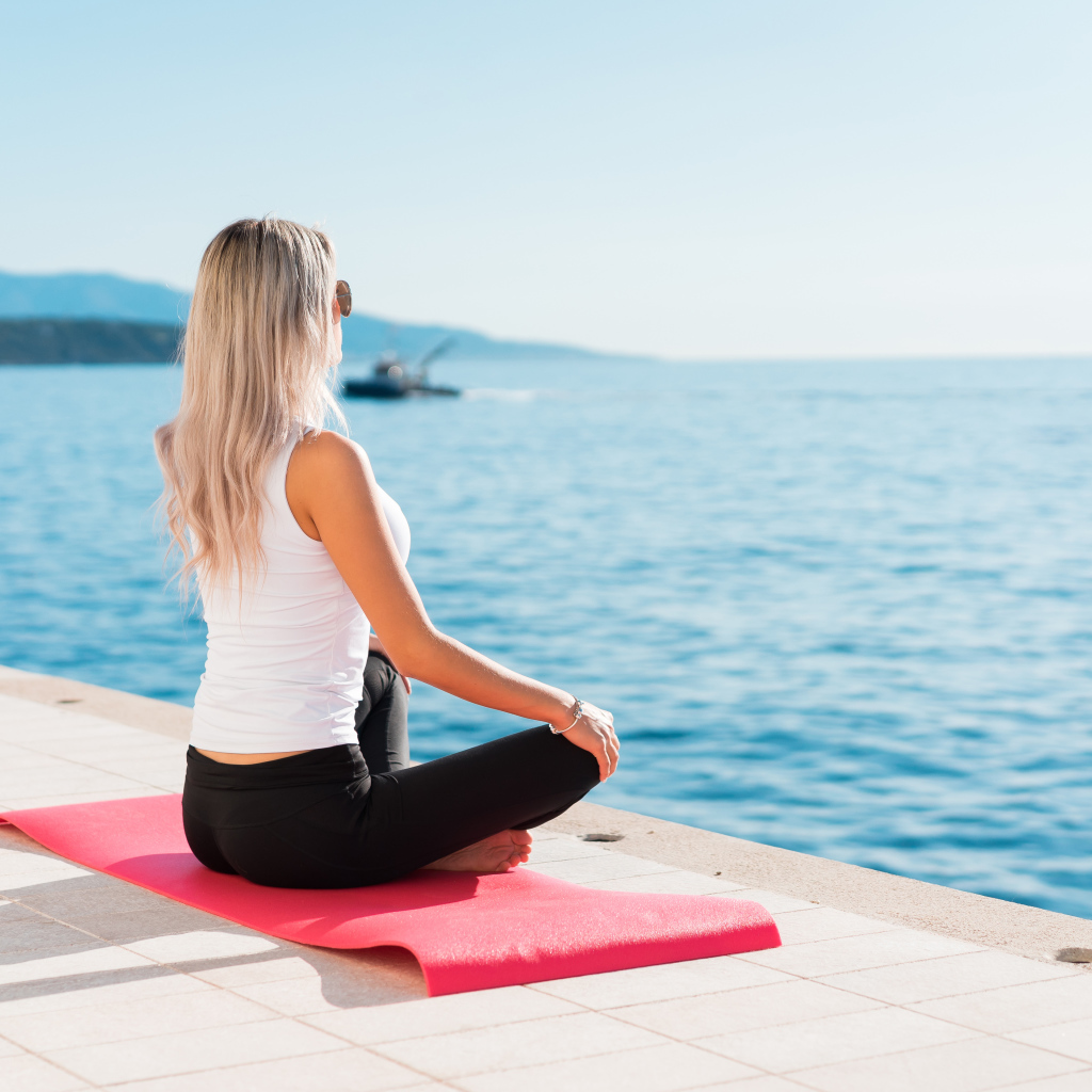 Девушка медитирует на берегу моря 