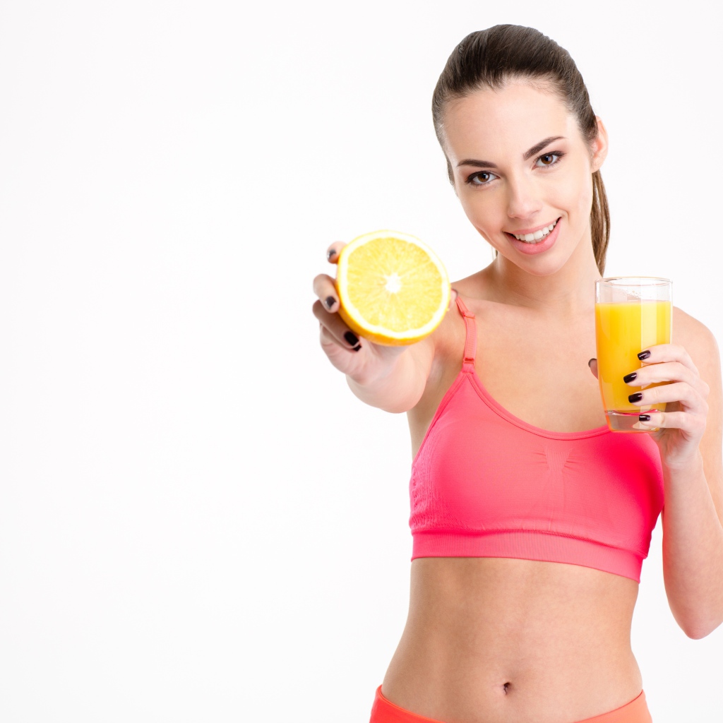 Девушка со стаканом сока и апельсином на белом фоне