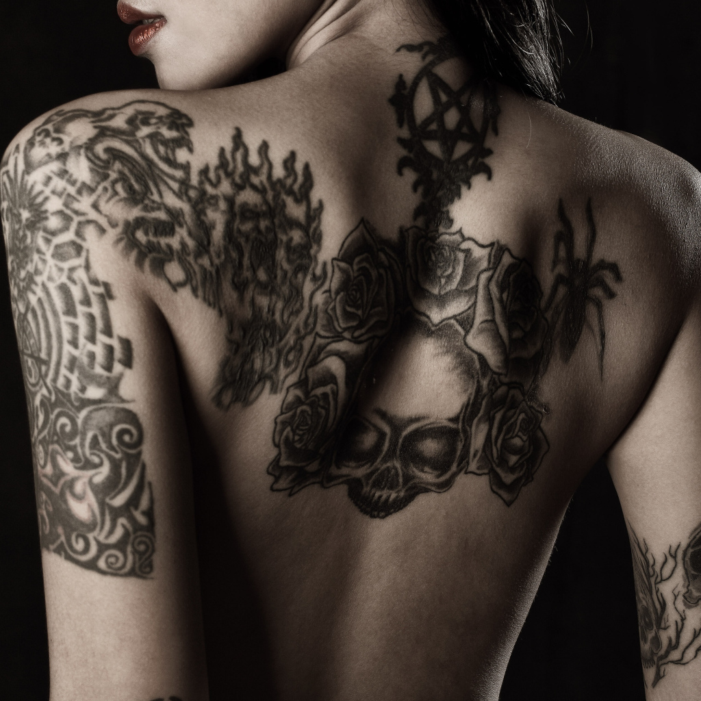 Девушка с татуировками на руках и спине