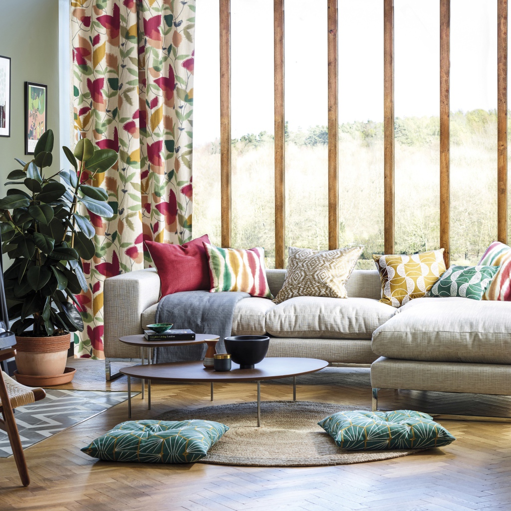 Серый мягкий диван стоит у большого окна в комнате