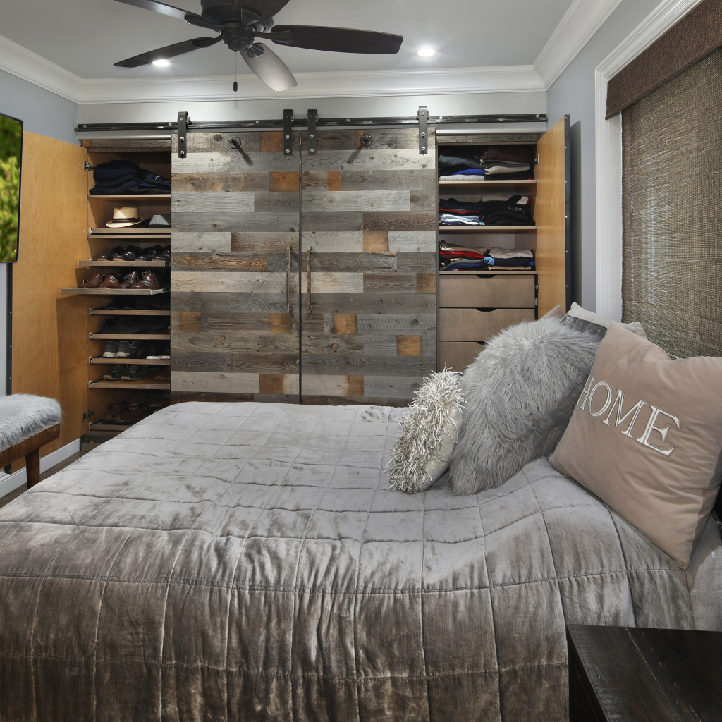 Большая серая кровать в спальне с деревянным интерьером