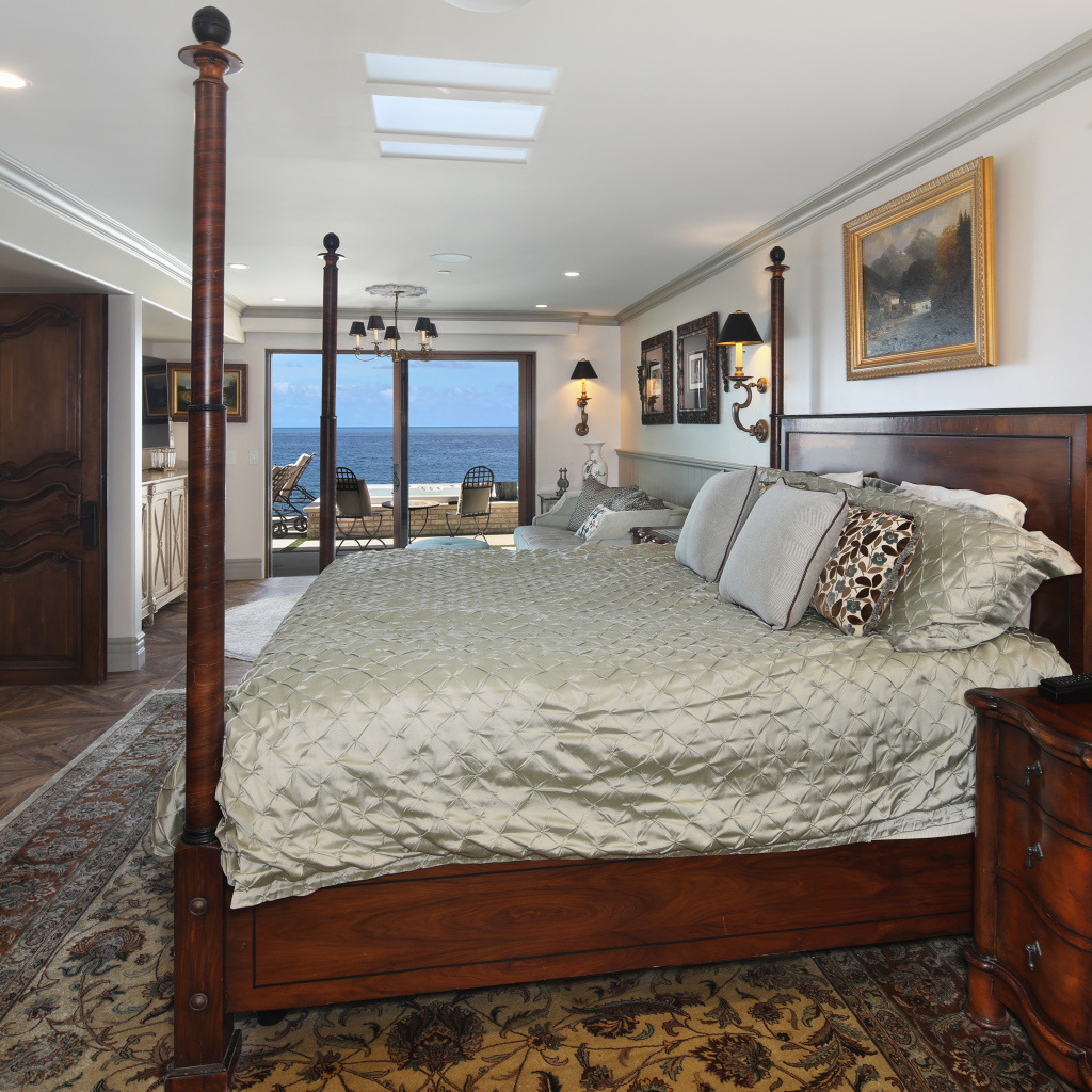 Большая деревянная кровать в спальне с видом на море 