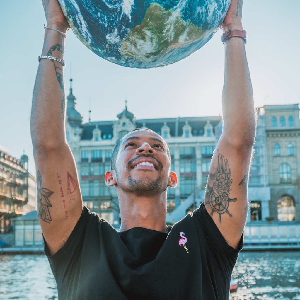 Мужчина с татуировками на теле с землей в руках 
