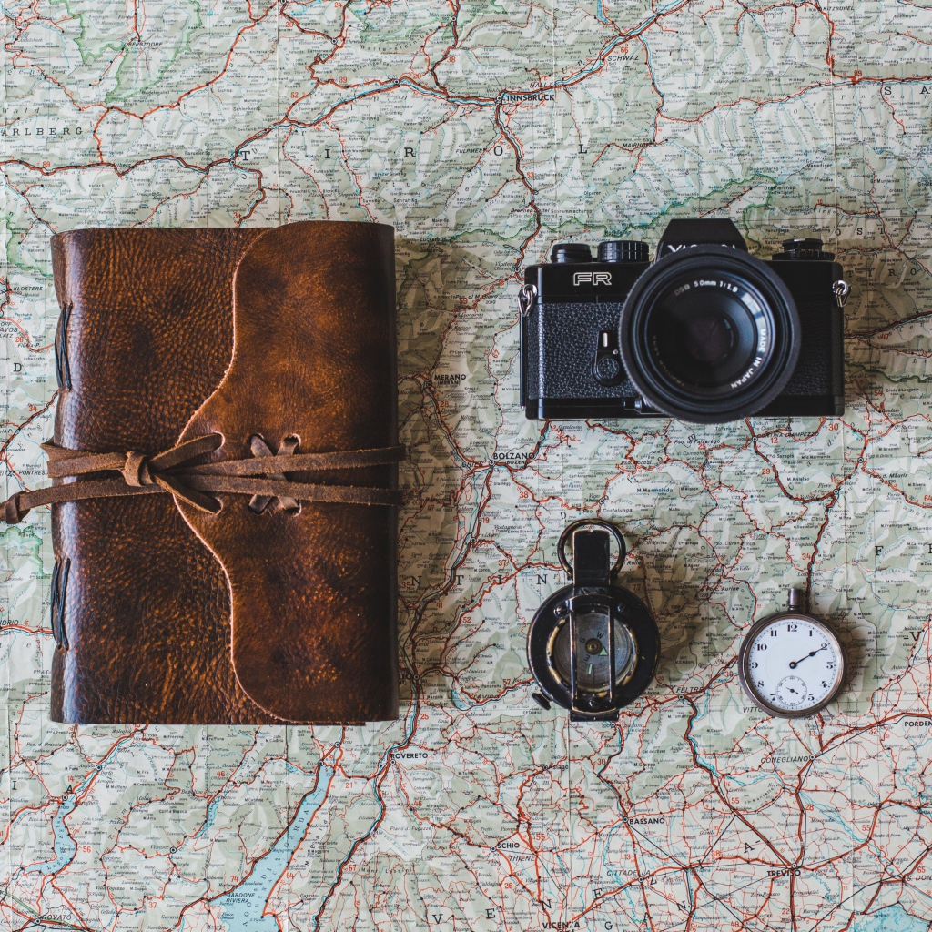 Старый фотоаппарат, компас, часы, блокнот и карта на столе