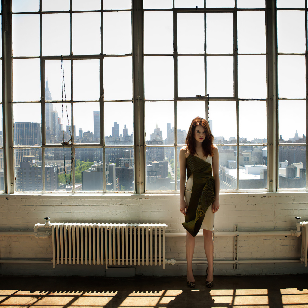 Популярная актриса Эмма Стоун стоит у большого окна