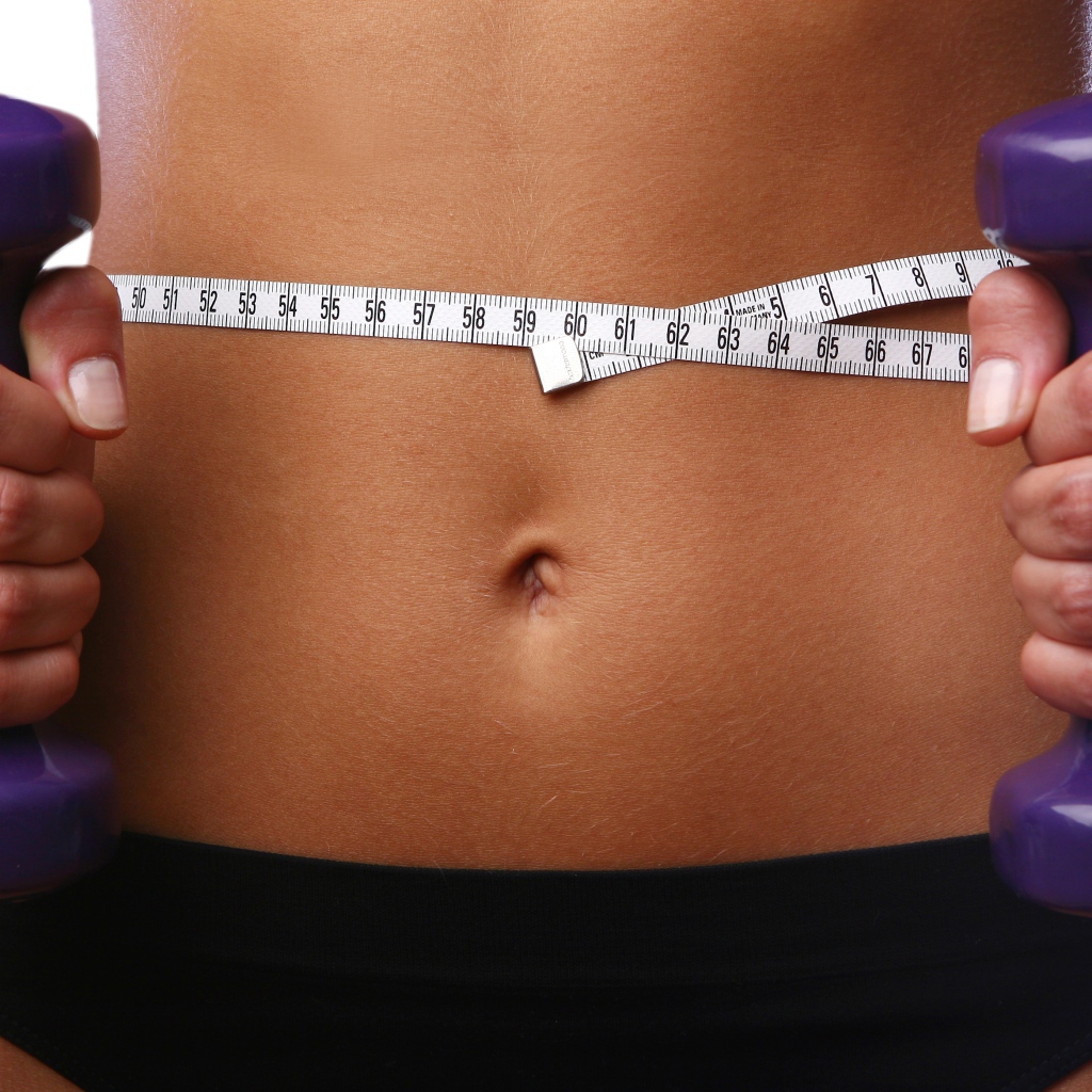 Стройная спортивная девушка с гантелями в руках 