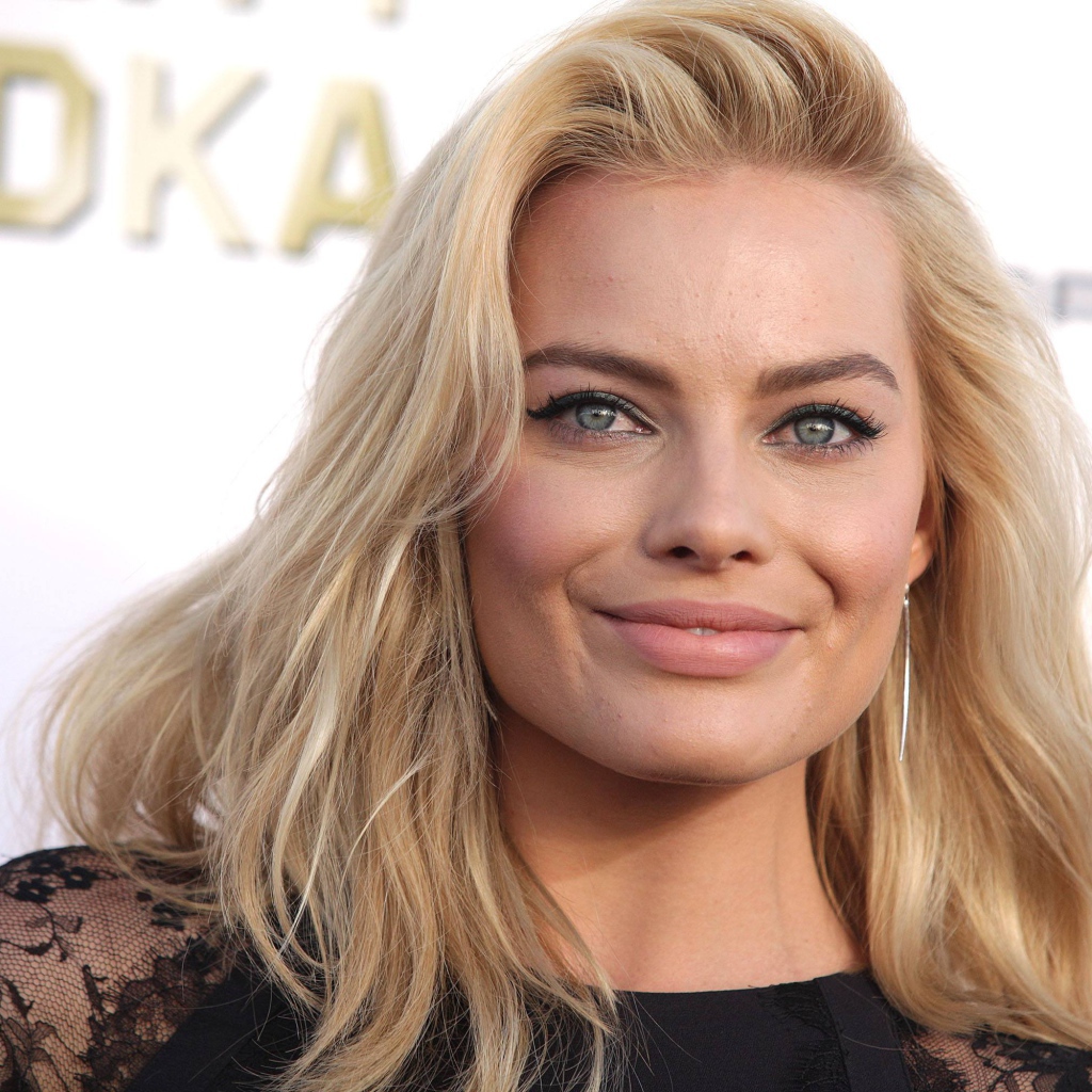 Улыбающаяся блондинка, актриса Марго Робби у стены