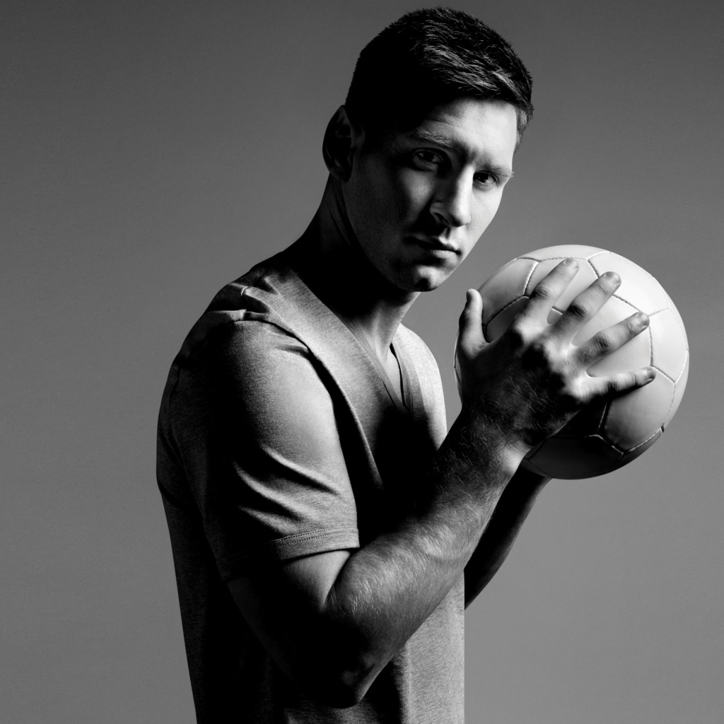Футболист Лионель Месси с мячом в руках на сером фоне