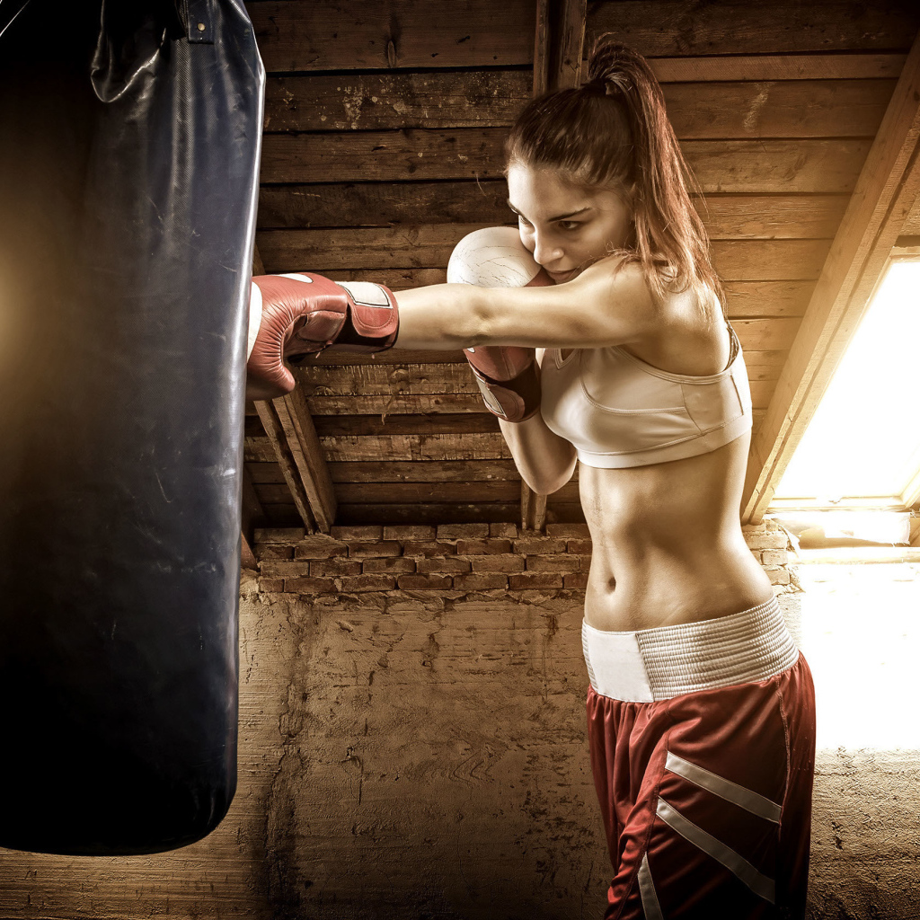 Спортивная девушка бьет боксерскую грушу 