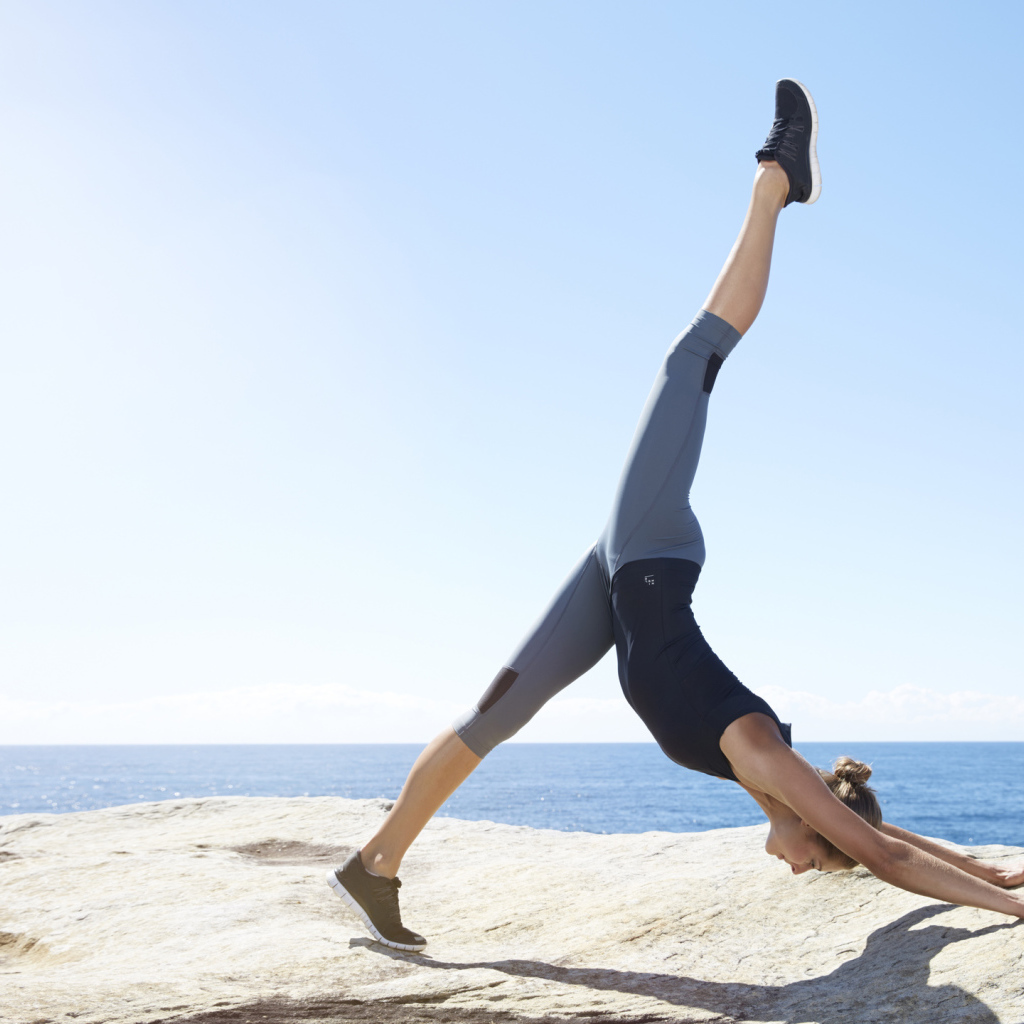 Спортивная девушка делает упражнения на берегу моря 