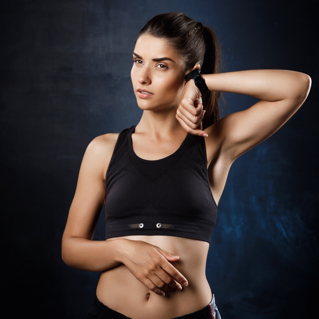 Спортивная девушка в черном костюме с часами на руке