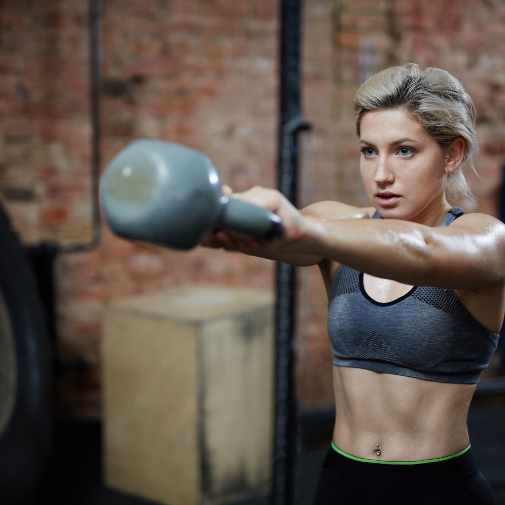 Спортивная девушка с гантелей в спортзале