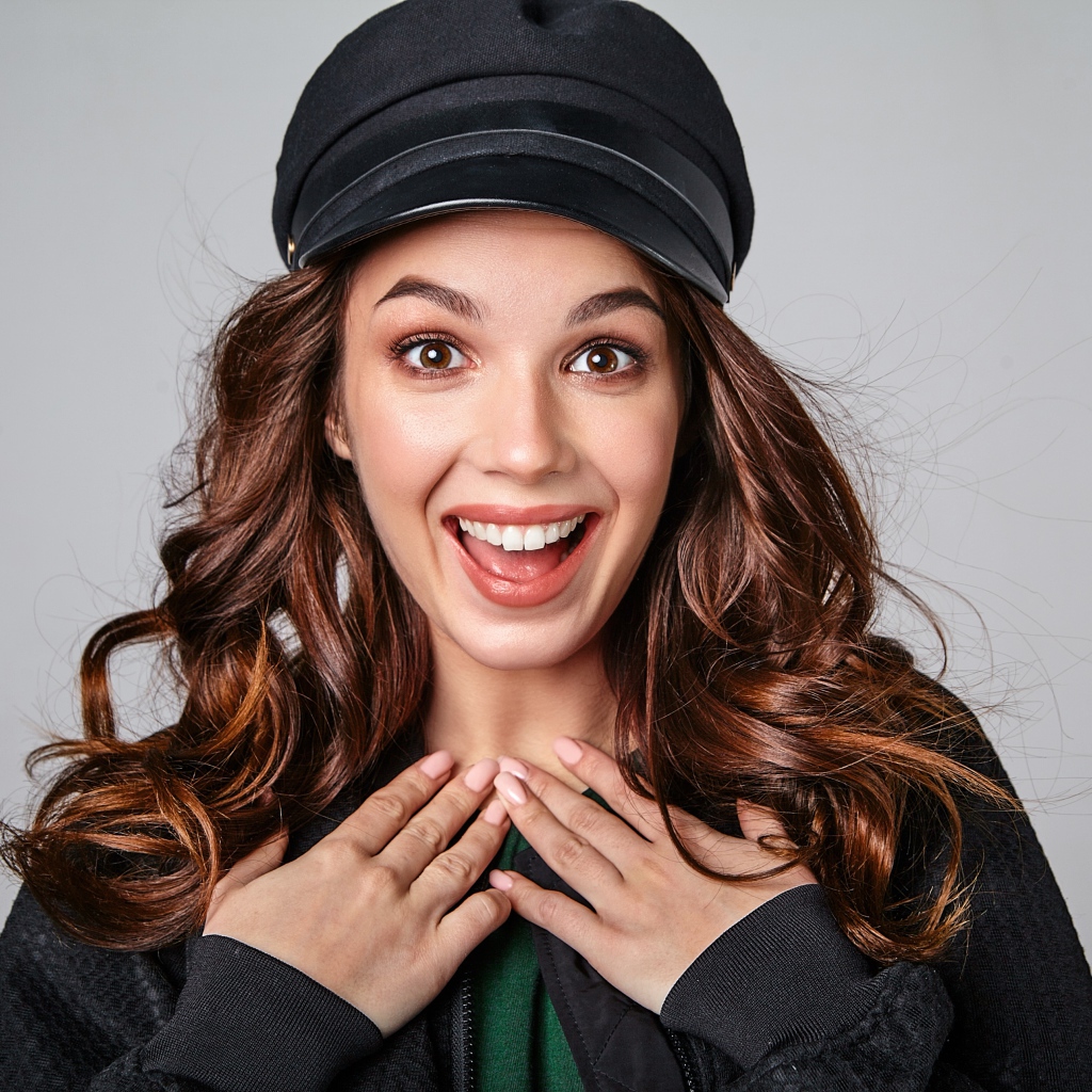 Удивленная кареглазая девушка в черной кепке