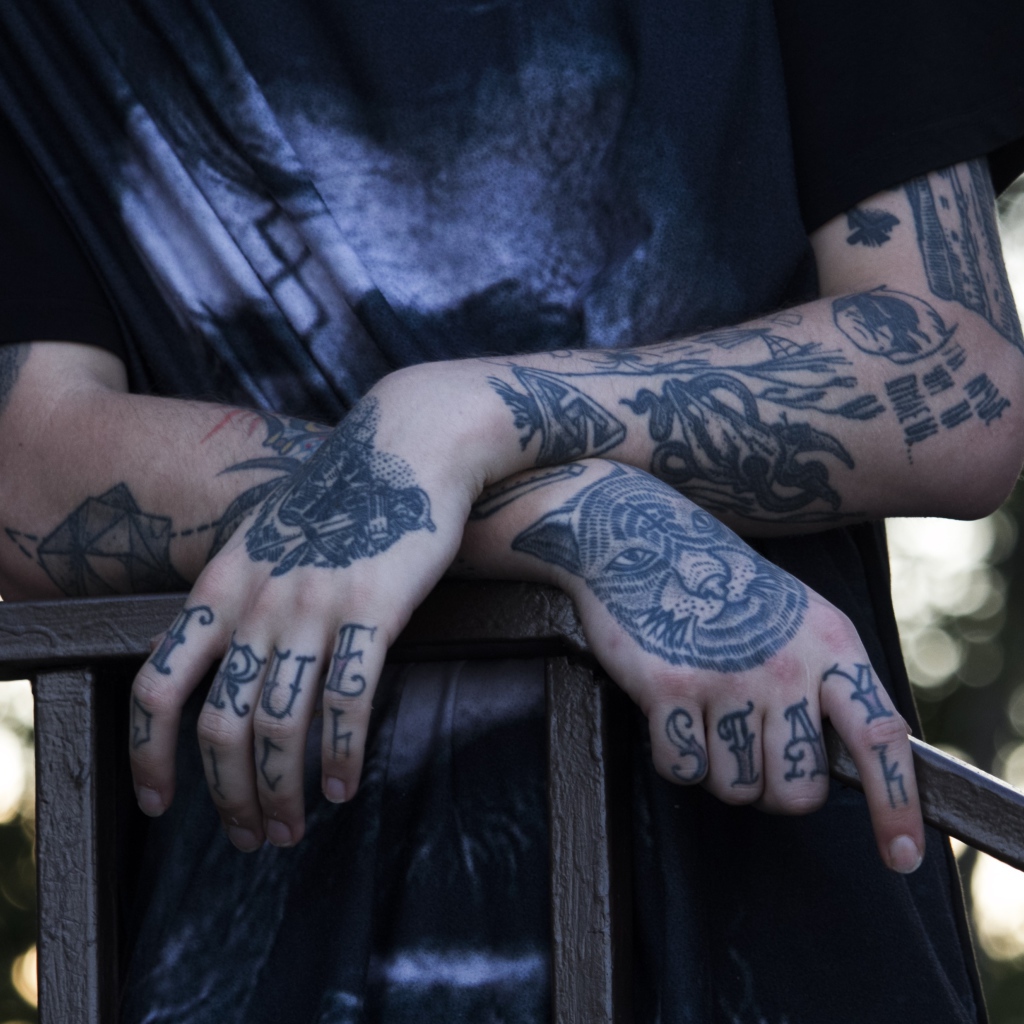 Татуировки на руках у парня в черной футболке 