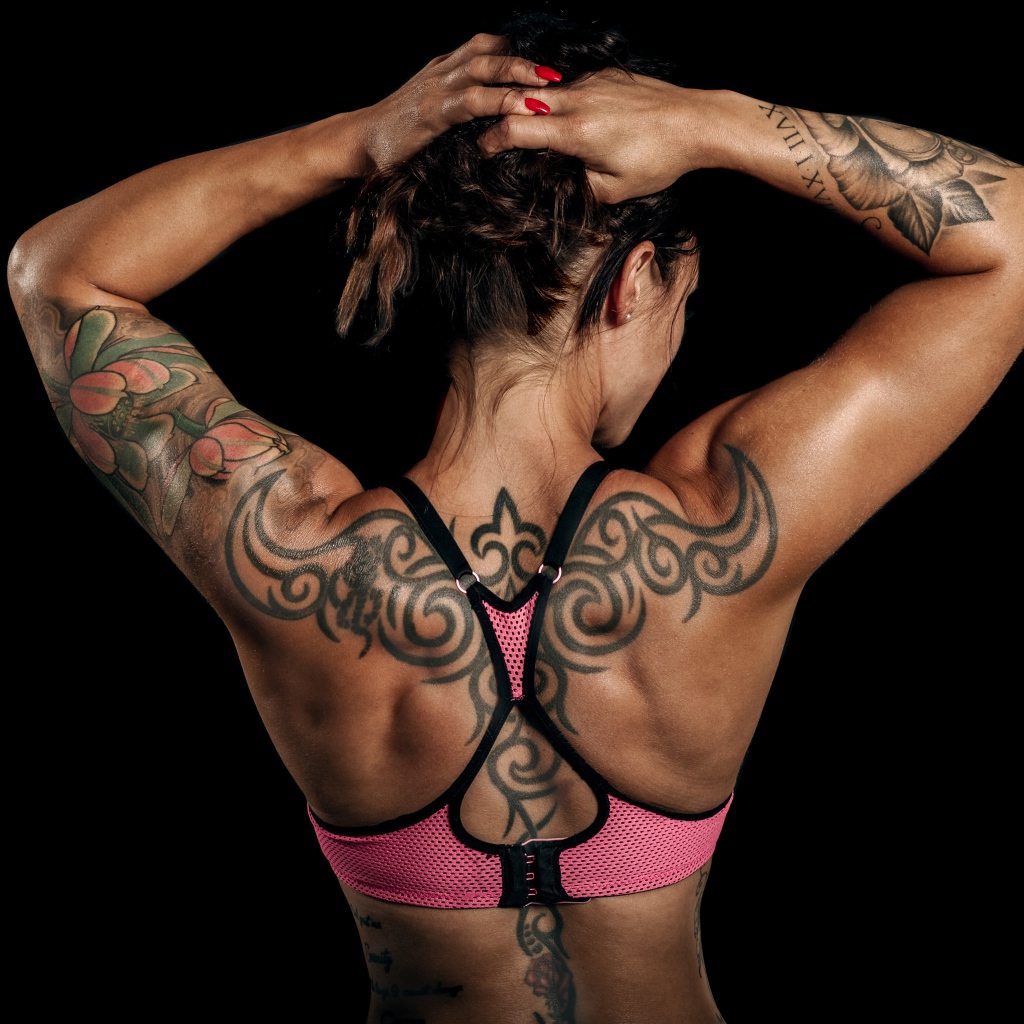 Татуировки на теле спортивной девушки на черном фоне