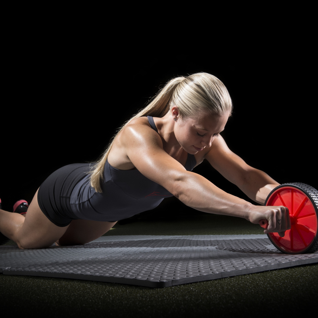 Девушка занимается фитнесом с колесом