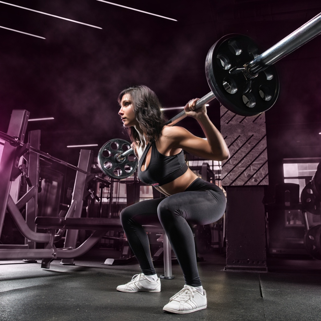 Девушка тяжелоатлет поднимает штангу в спортзале
