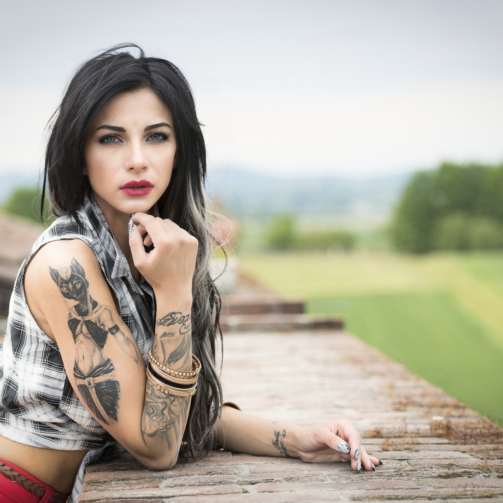 Молодая девушка брюнетка с татуировками на руках