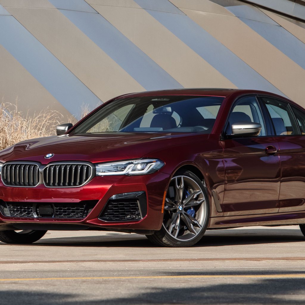 Бордовый седан BMW M550i XDrive, 2021 года у здания