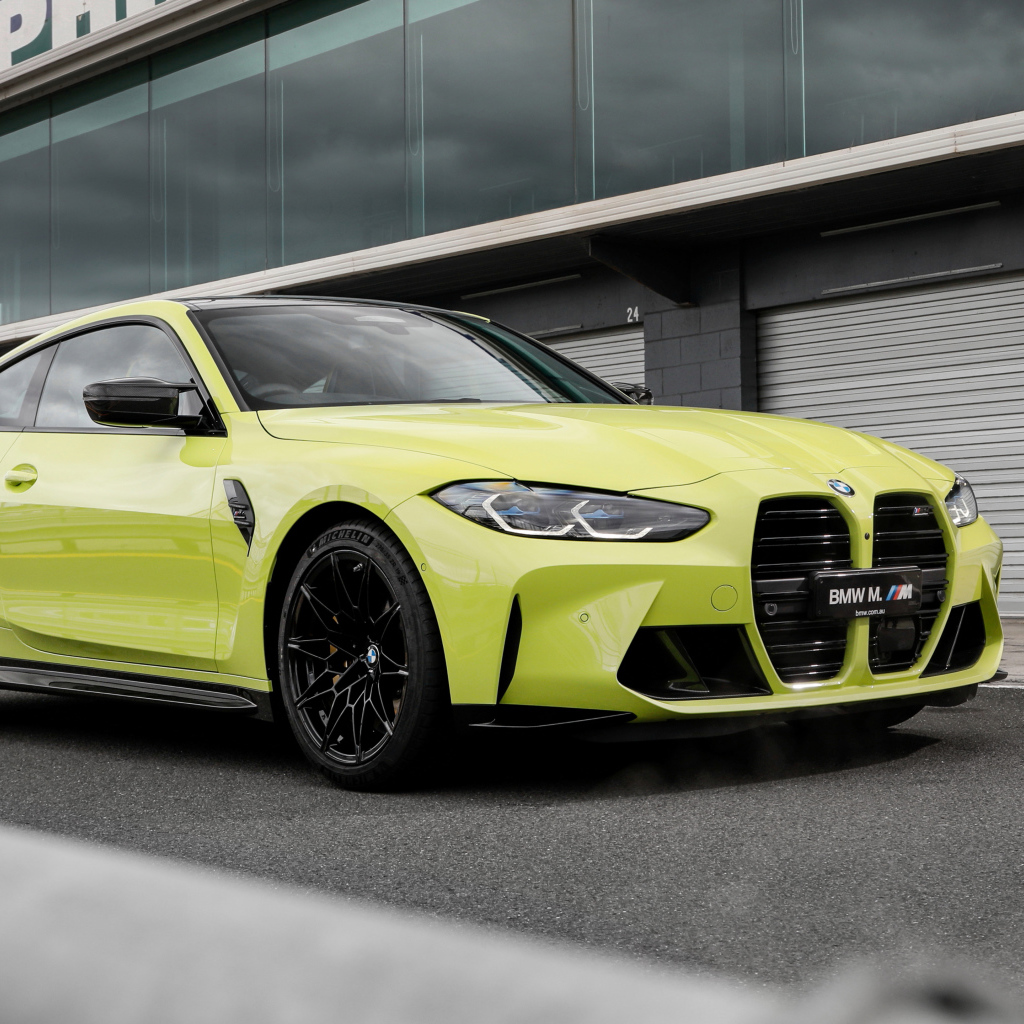 Желтый автомобиль BMW M4 Competition 2021 года у здания