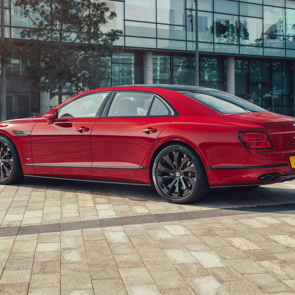 Красный автомобиль Bentley Flying Spur V8 2020 года у здания 