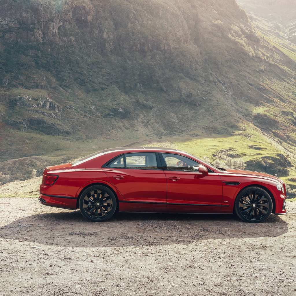 Красный автомобиль Bentley Flying Spur V8 2020 года у горы 