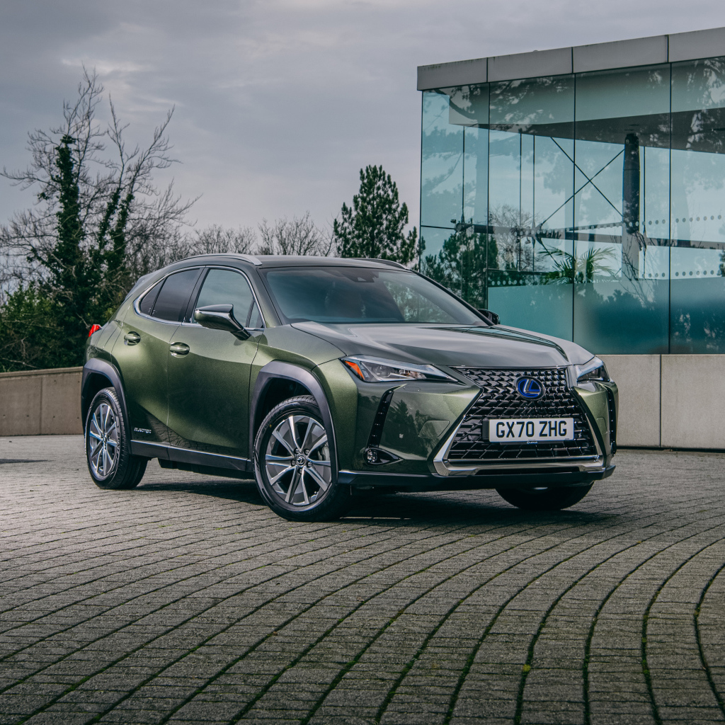 Зеленый автомобиль Lexus UX 300e 2021 года у стеклянной стены