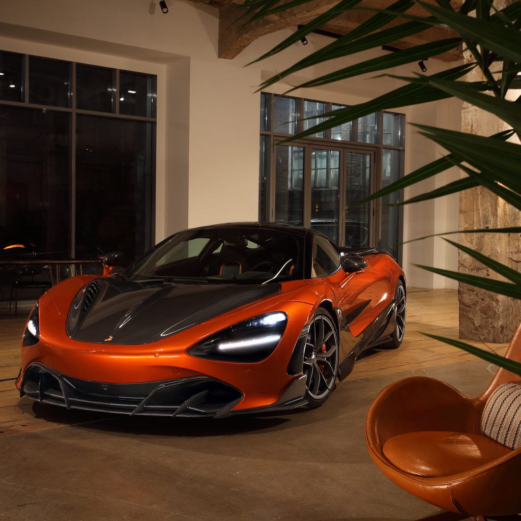 Оранжевый автомобиль  McLaren 720S у дома с креслом