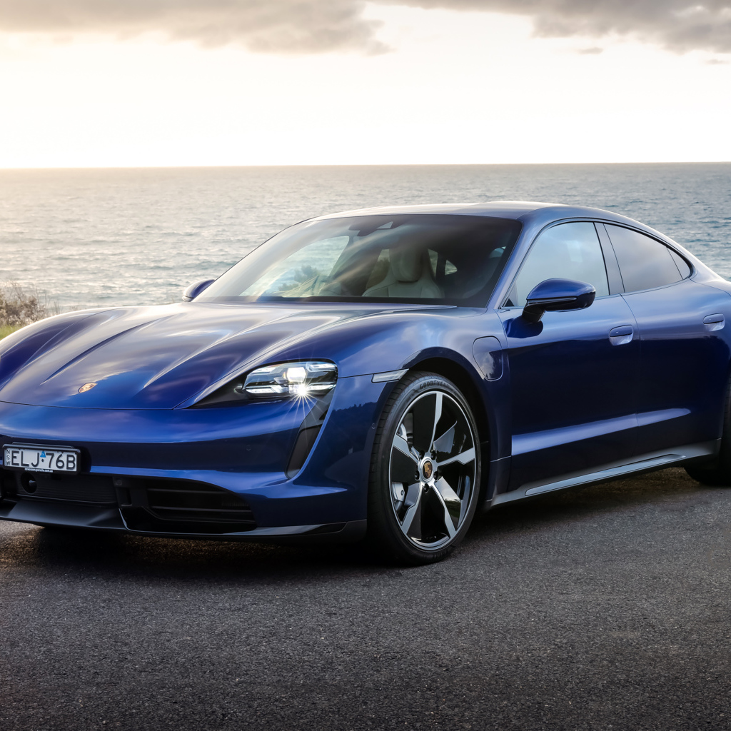 Синий автомобиль Porsche Taycan Turbo у моря