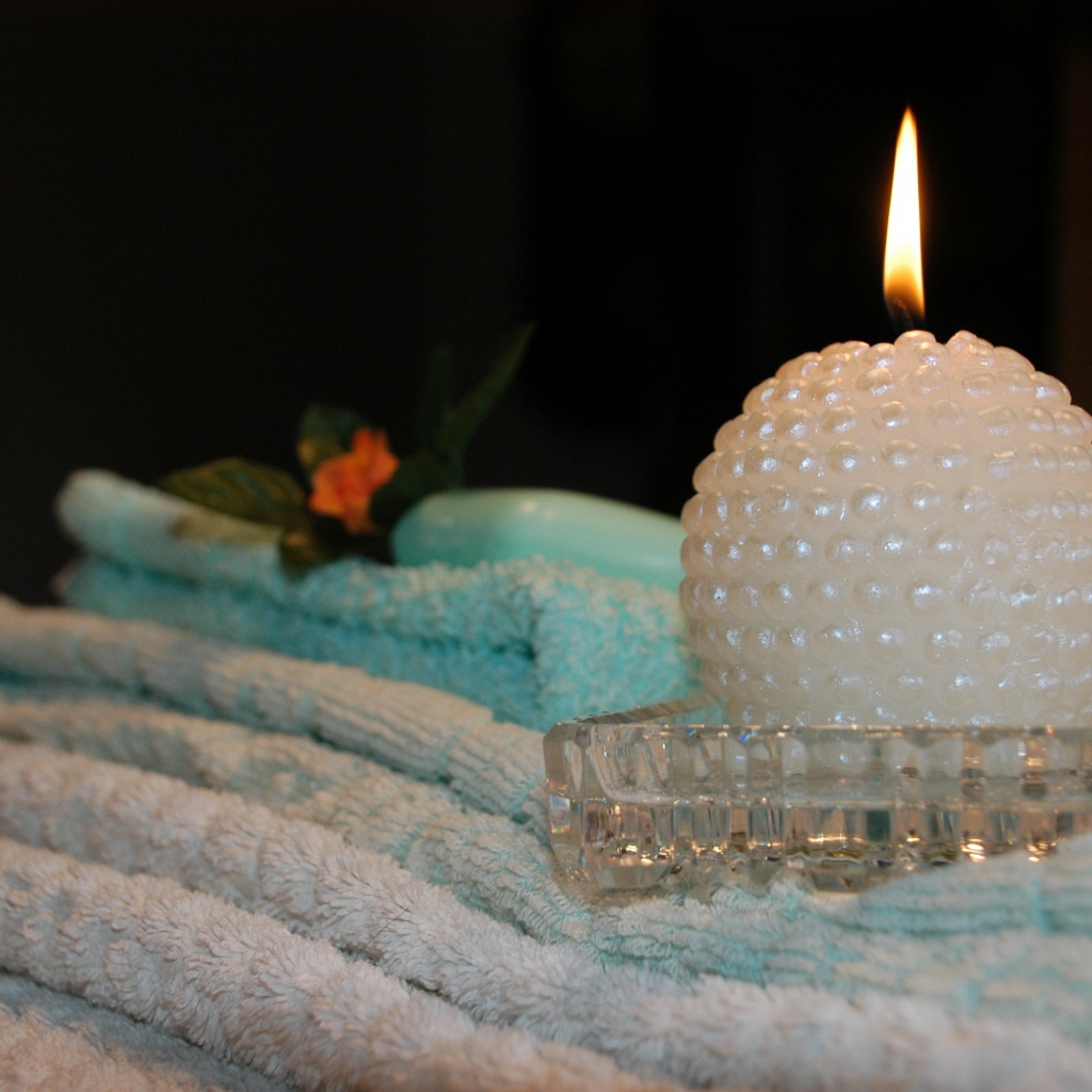 Красивая зажженная свеча с полотенцами