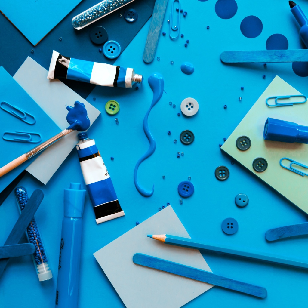 Синие канцелярские предметы, бумага и краски на столе 