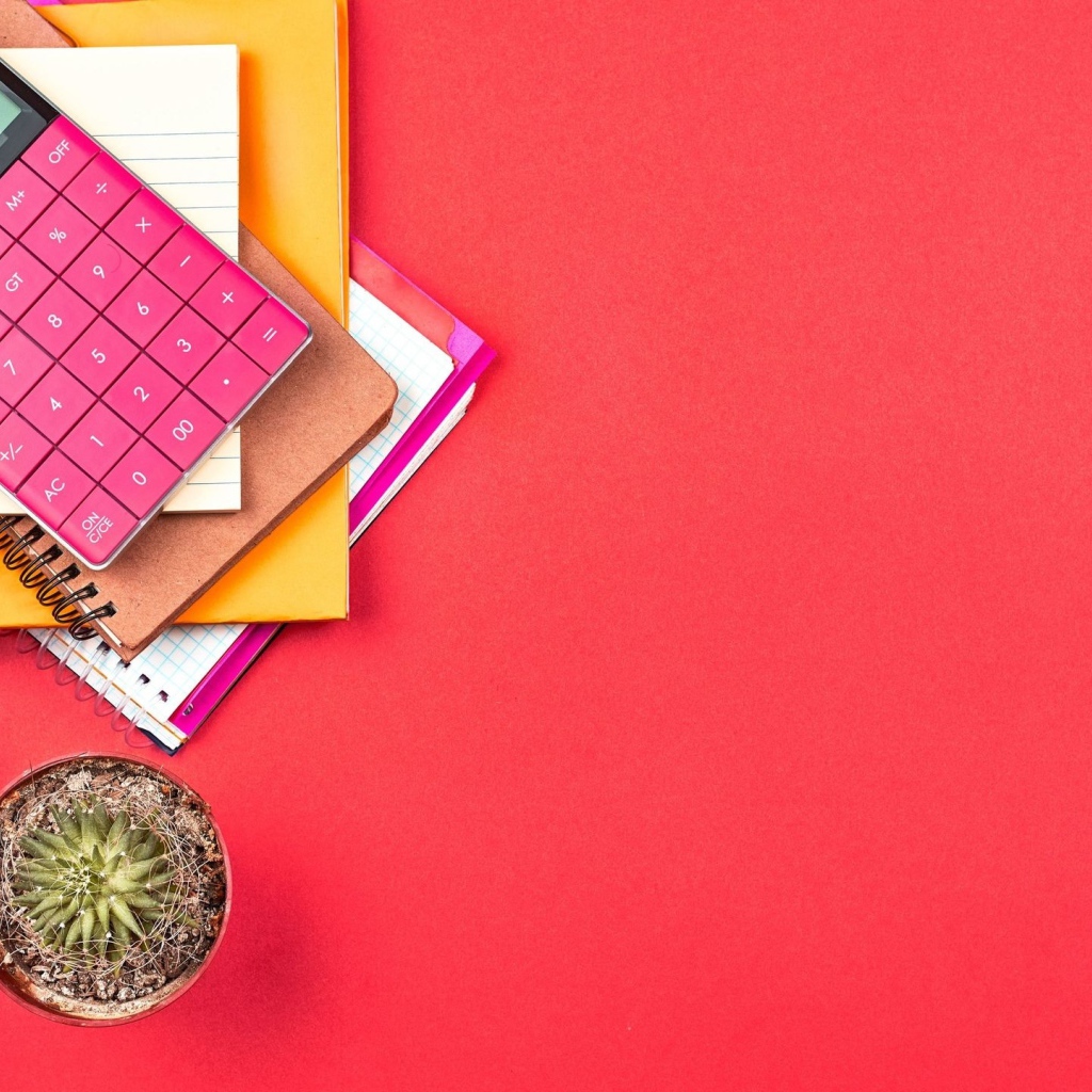 Калькулятор с очками и блокнотами на розовом фоне 