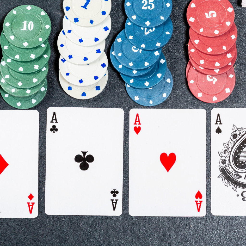 Четыре туза с фишками на сером столе