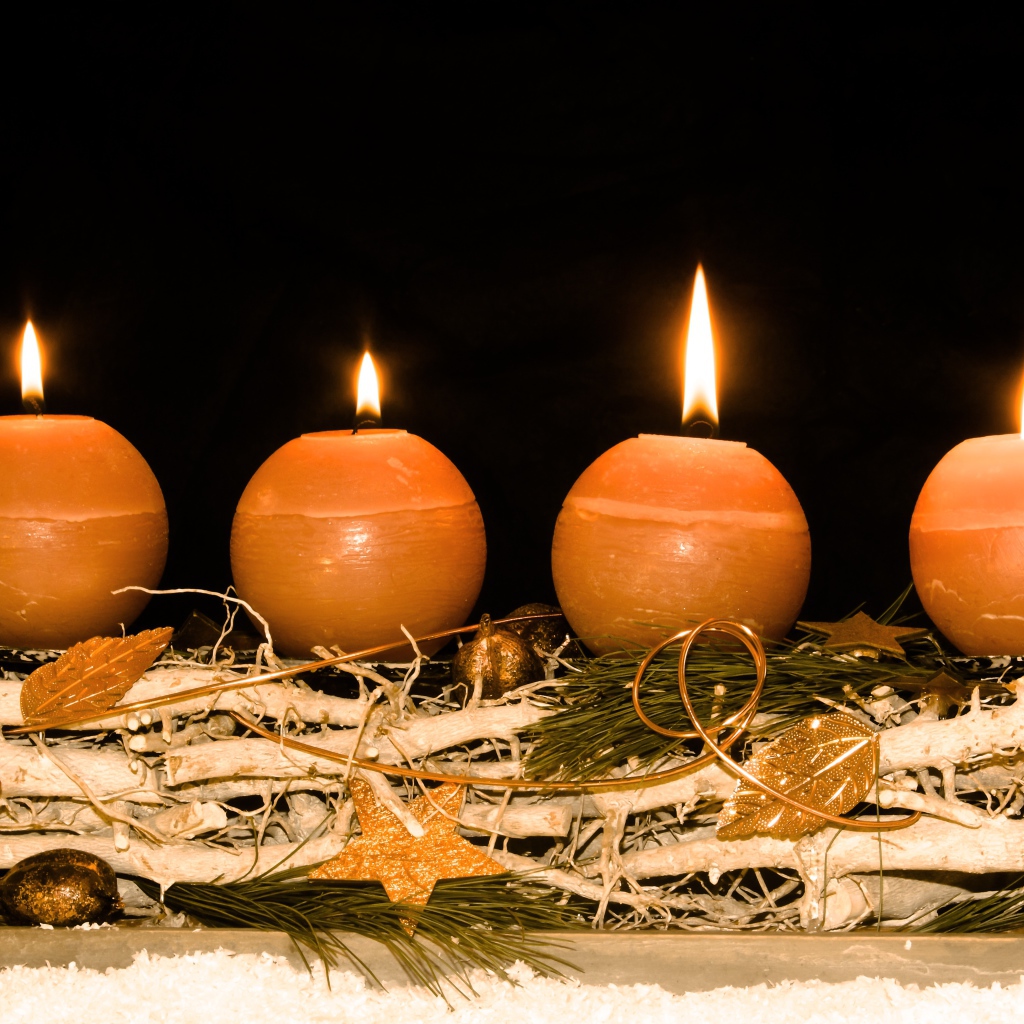Четыре круглые зажженные свечи на черном фоне