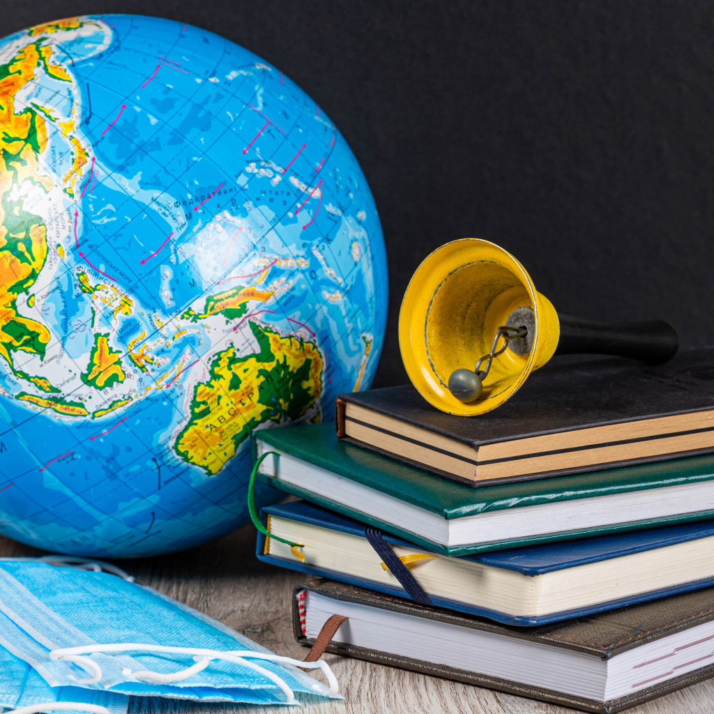 Глобус, книги, колокольчик и медицинские маски 