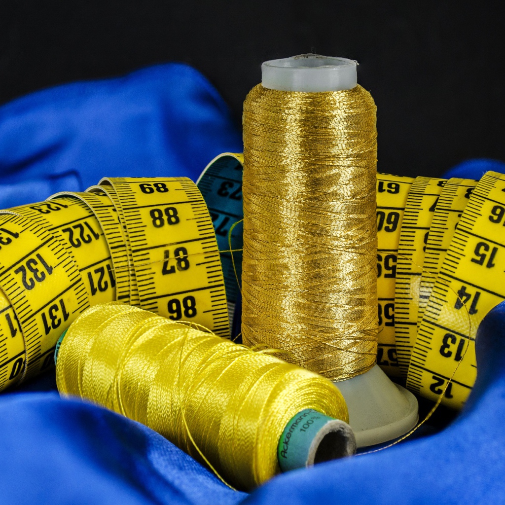 Золотые нитки и сантиметр на голубой ткани 