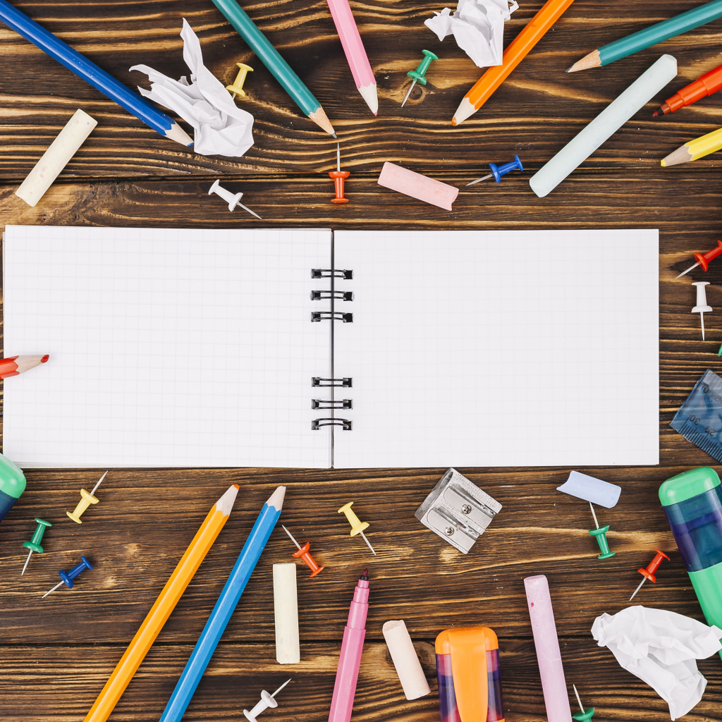 Открытый блокнот с ручками  на столе 