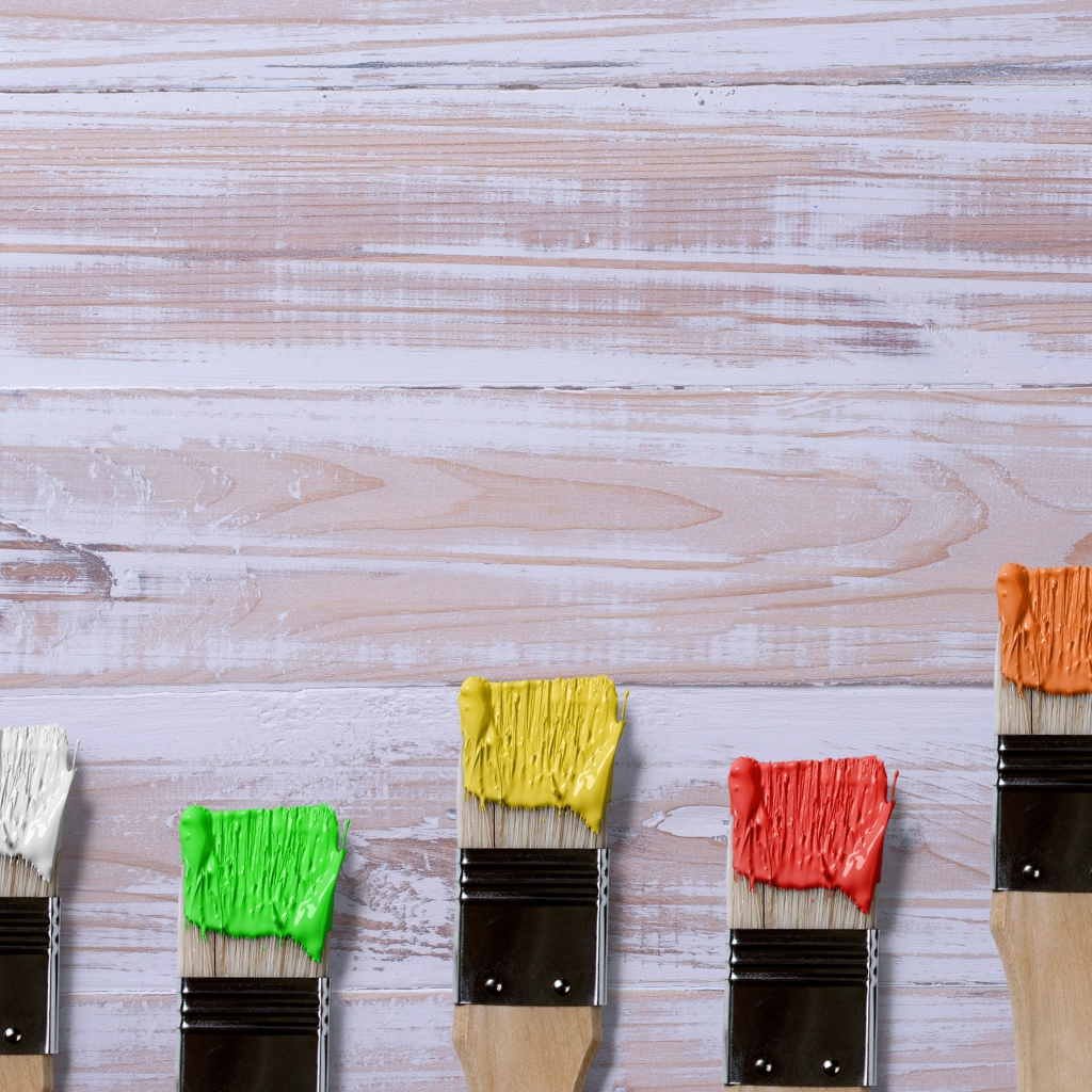 Кисточки в краске на деревянном фоне