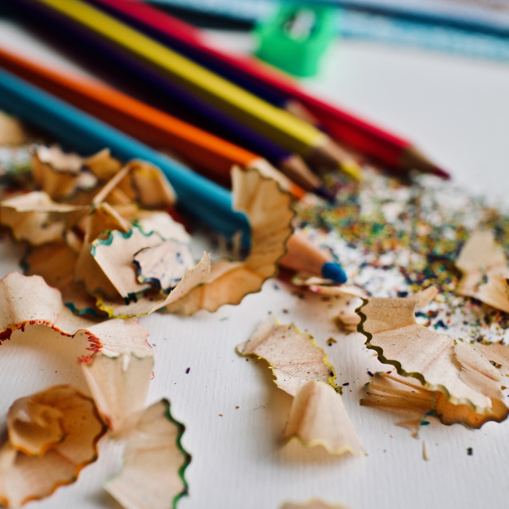 Карандаши со стружкой на сером столе 