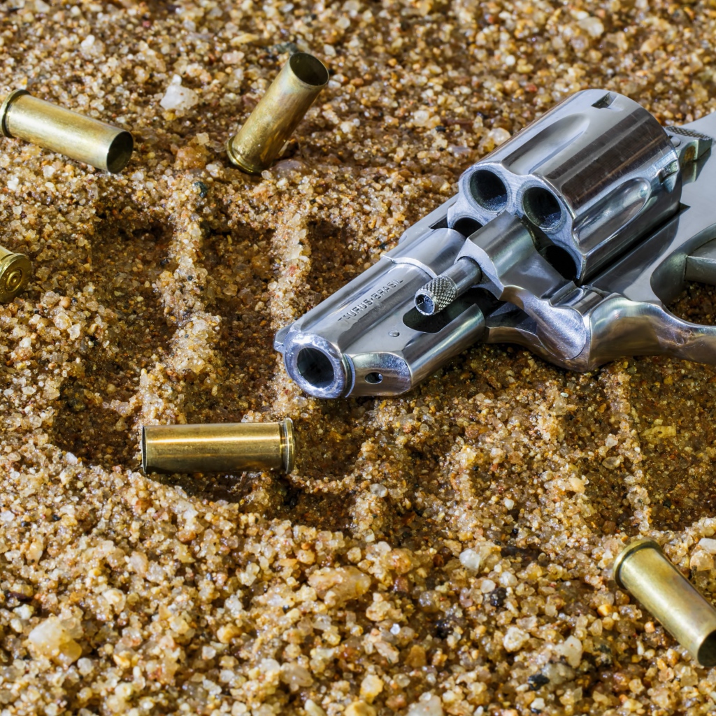 Револьвер с гильзами лежат на песке