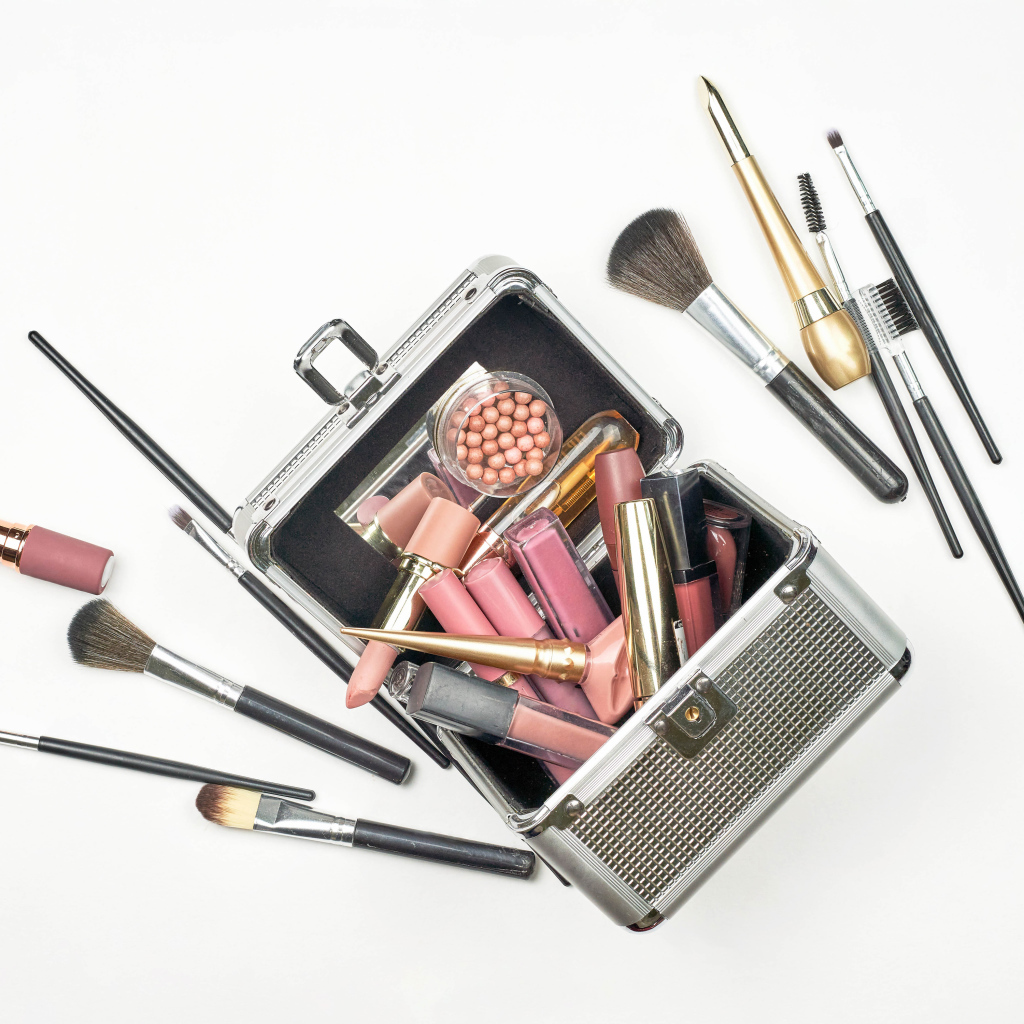 Набор косметики в чемодане на белом фоне