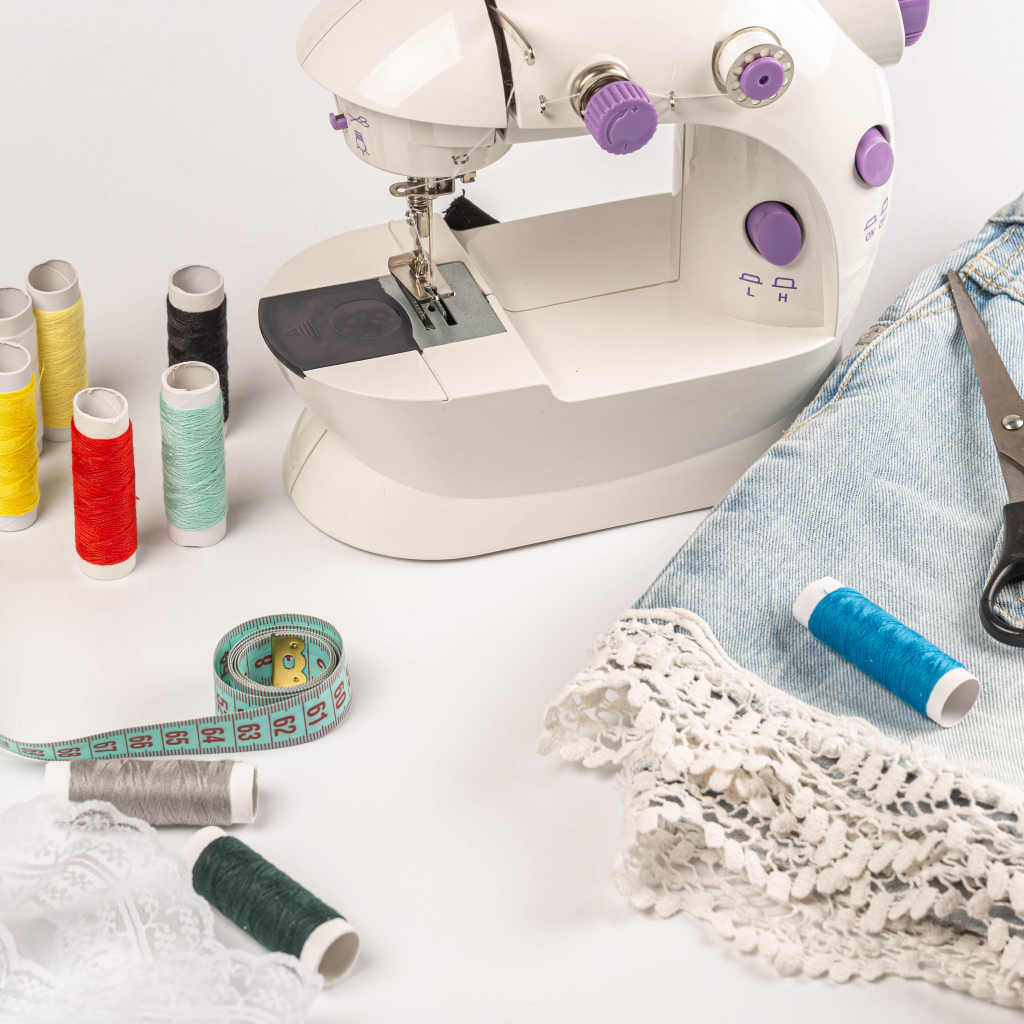 Швейная машинка,юбка и нитки на белом фоне 