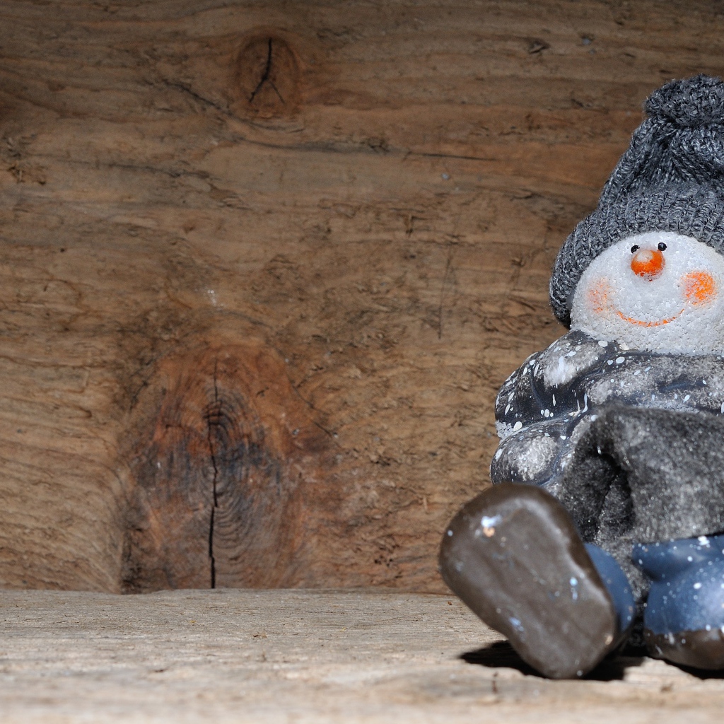 Фигурка снеговик у деревянной стены